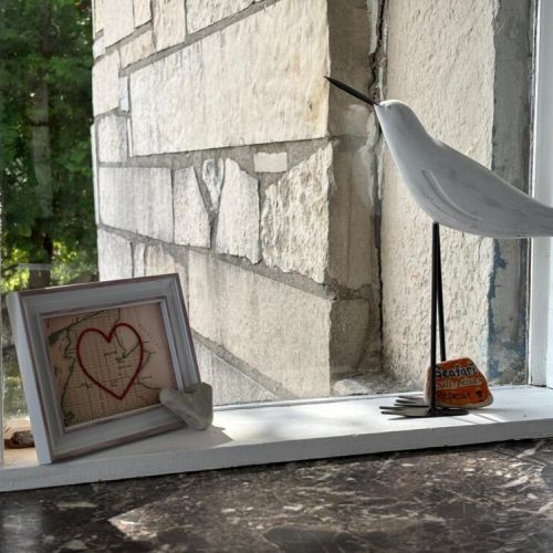 A heart-shaped map art piece and coastal bird sculpture bring charm to the windowsill.