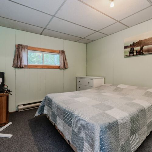 A comfortable bedroom with a soft blue bedspread, fan, and small TV for relaxation.