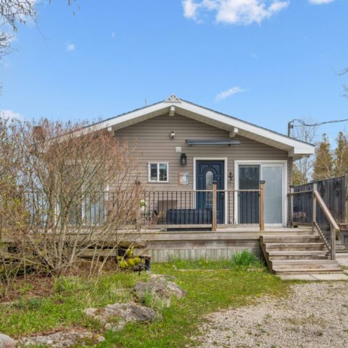 Inviting front porch entrance surrounded by mature trees and natural beauty.