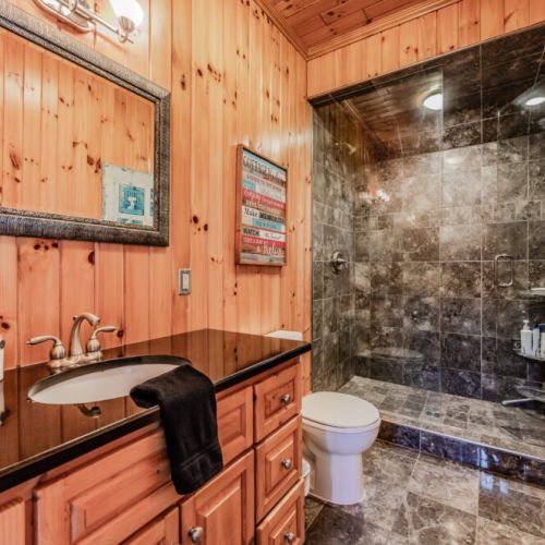 Modern full bathroom with granite vanity, glass walk-in shower, and wood accents—perfect for unwinding after lakeside adventures.