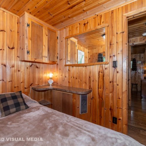 Rustic bedroom with pine walls and cozy bedding—sleep surrounded by nature’s quiet.