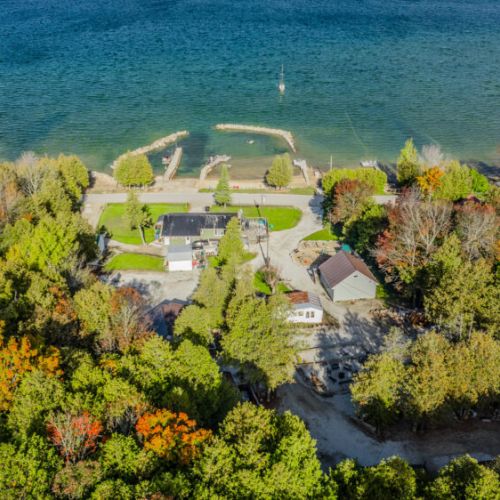 A scenic view of the cottages set against the backdrop of lush greenery and a calm lakeside.