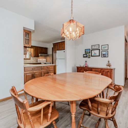 Gather around the large wooden dining table for meals, games, or conversation, with a cozy view into the fully equipped kitchen just steps away.