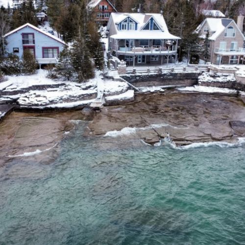 Snow-dusted shoreline and turquoise waters create a breathtaking lakeside scene.