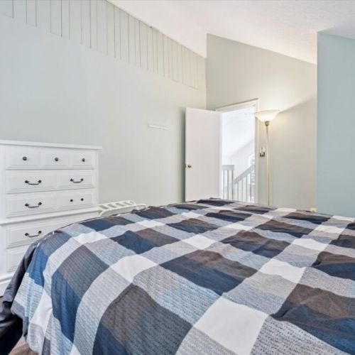 Bright bedroom with vaulted ceiling, queen bed, and plenty of storage