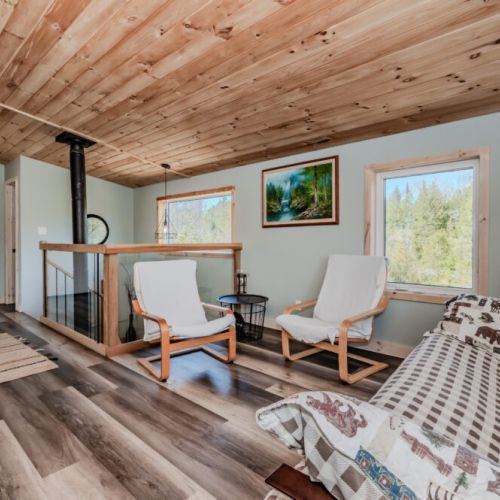 Serene upstairs sitting area with peaceful forest views, perfect for reading, morning coffee, or quiet moments between hikes and lake swims.