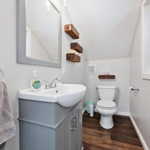 Bright bathroom with modern vanity, open shelving, and warm wood-tone floors