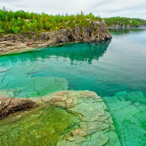 Experience the enchanting beauty of The Grotto at Bruce Peninsula National Park. Marvel at the clear, turquoise waters that pool within the rugged limestone cliffs, inviting you for a refreshing swim or a moment of reflection amidst the tranquil surroundings.