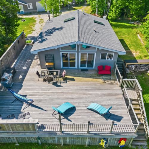 A private waterfront cottage with a spacious deck, outdoor seating, and forest views. Perfect for summer travel, outdoor living, and relaxed coastal getaways.