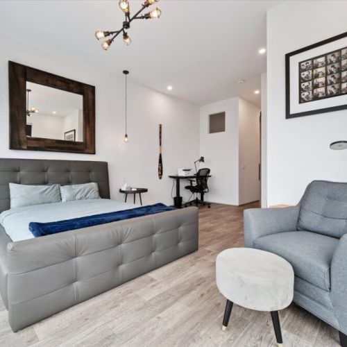 A spacious primary bedroom with soft textures, modern lighting, and a calm layout that invites rest after a day outdoors.