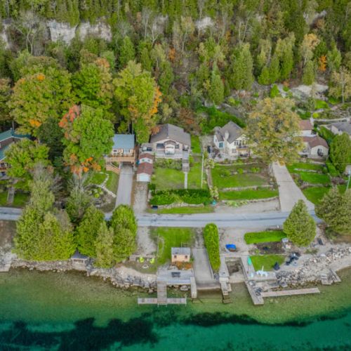An aerial perspective of the peaceful neighborhood, showcasing the cottage’s proximity to the water and its lush surroundings.
