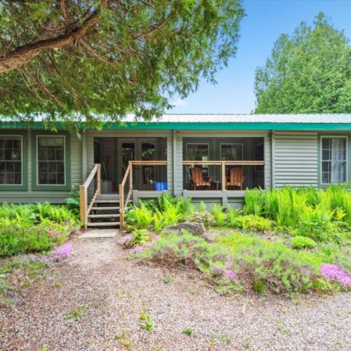 Step into your woodland retreat via a cozy front porch framed by vibrant ferns and blooms. This peaceful entryway is perfect for that first morning coffee or a post-adventure wind-down.