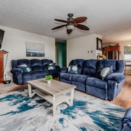 Unwind in the cozy living room, complete with plush blue sofas and a fireplace—perfect for family gatherings or a quiet evening in.