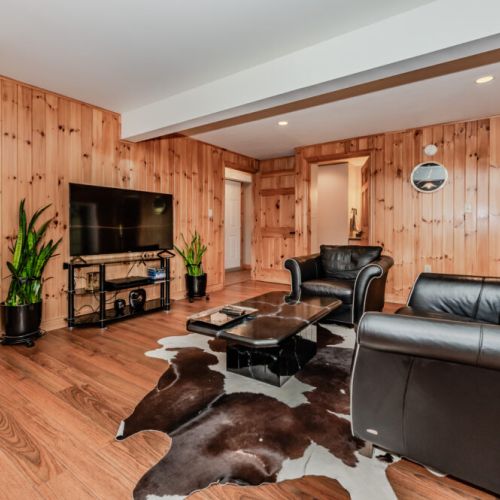 Relax after a day of exploring in this rustic-chic lounge with plush leather seating, flat-screen TV, and warm pine walls—perfect for unwinding in your cottage getaway.