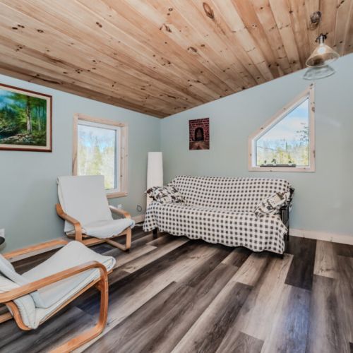 Relax in this cozy upper-level lounge with forest views, soft seating, and a flat-screen TV—perfect for unwinding after outdoor adventures.