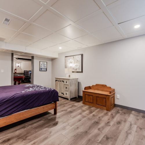 Spacious lower-level bedroom with warm lighting and rustic-modern décor, perfect for unwinding after a day of lakeside exploration or cozy cottage evenings with the family. Ideal for a peaceful vacation escape.