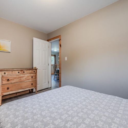 The bedroom includes a charming wooden dresser and a rocking chair, adding to the cabin's cozy atmosphere.