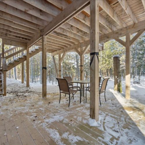 Covered outdoor patio area beneath the cabin—perfect for sitting outside in any season. A sheltered spot for fresh air, conversation, or a peaceful break.