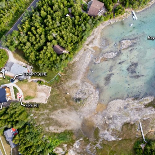 Aerial view of Fathom Hideaway showcasing the waterfront, fire pit, trampoline, cornhole, and beautiful Hay Bay shoreline.