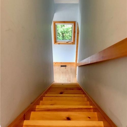 Head upstairs to the loft level, where warm wood details continue throughout the cottage.