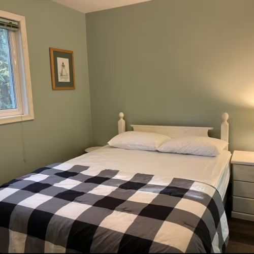A peaceful main floor bedroom with soft lighting, cozy bedding, and woodland views — the perfect place to rest after a day of exploring the Peninsula.