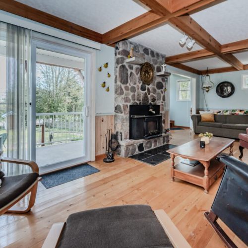 The living room extends to a patio view, offering seamless indoor-outdoor living. The sliding doors let in natural light, enhancing the charm and atmosphere.