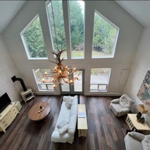 A stunning view of the living room from the loft, where light pours through the floor-to-ceiling windows and nature feels just a step away.