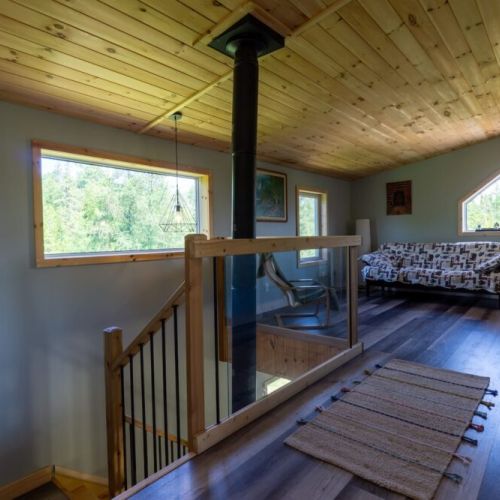 Bright upper-level space overlooking the main floor, complete with rustic charm, cozy seating, and a view of the treetops.