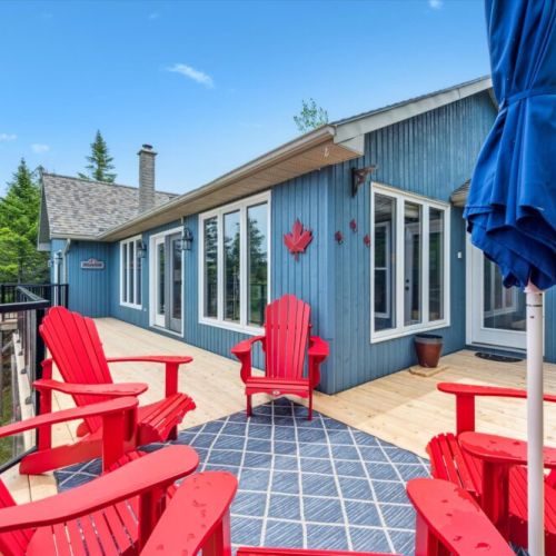 Enjoy morning coffee or sunset chats from the spacious deck, complete with iconic red chairs and a view through the treetops.
