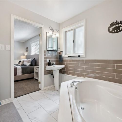 Bright ensuite bathroom featuring a relaxing soaker tub and convenient access to the primary bedroom.