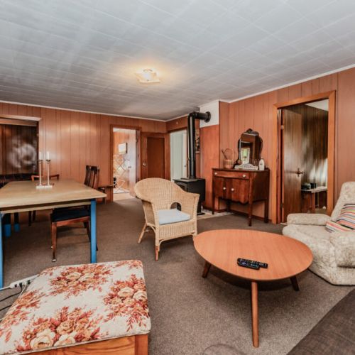 Relax in a spacious rustic lounge with comfy seating, a wood stove, and vintage charm—ideal for cozy nights, family gatherings, and unforgettable vacation memories in nature.
