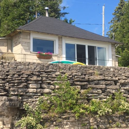 The stone cottage perched above the rocky shoreline.