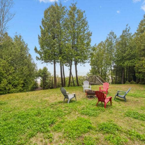 Private waterfront setting with a spacious grassy yard, mature trees, and direct access to the clear waters of Lake Huron.