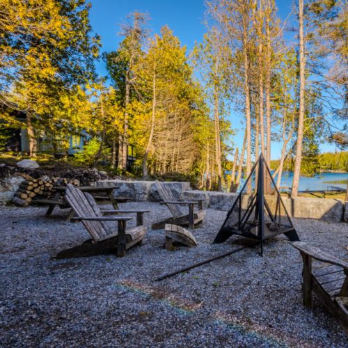 Relax at this serene waterfront vacation rental, featuring rustic Adirondack seating and a fire pit—perfect for cozy cottage getaways, lakeside retreats, and unforgettable outdoor experiences in nature.