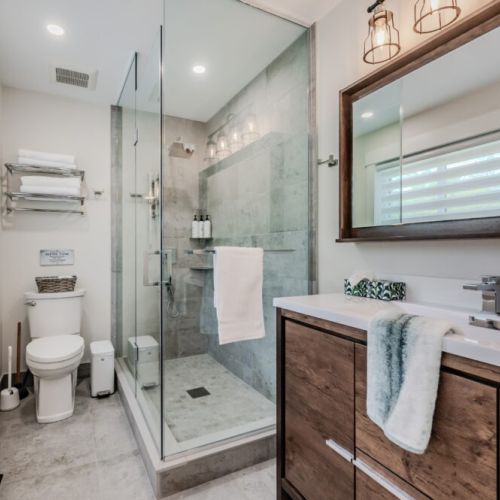 A well-appointed bathroom featuring a spacious glass-enclosed shower, modern fixtures, and elegant tile work. The vanity offers plenty of storage, complemented by contemporary lighting that enhances the clean and refreshing atmosphere.