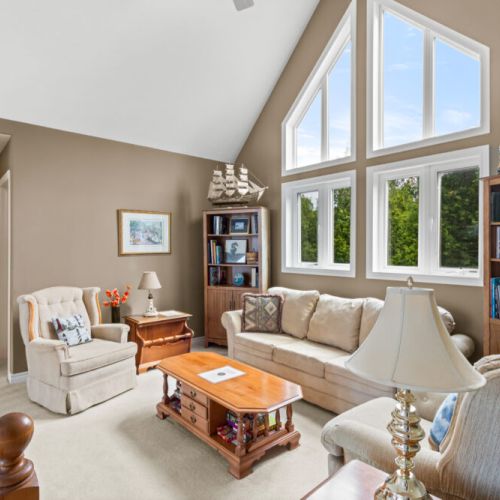 A bright and inviting loft sitting area with soaring windows, comfortable seating, and plenty of space to relax.