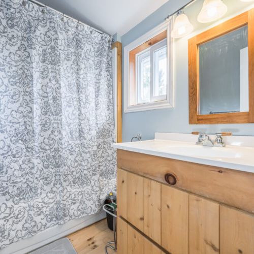 Relax in this beautifully appointed bathroom featuring natural wood accents and modern fixtures, perfect for unwinding after a day of exploring.