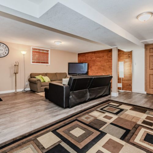 The lower-level lounge is a perfect spot for a cozy night in, with ample seating and a flat-screen TV for entertainment.