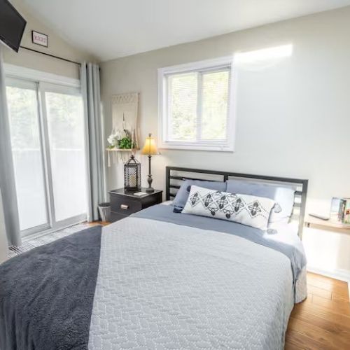 Wake up refreshed in the serene primary bedroom featuring a queen bed with soft linens, plenty of natural light, and sliding doors that open directly to the deck.
