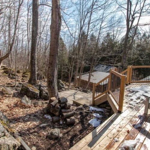 Wraparound deck and outdoor space nestled among mature trees and escarpment rock.