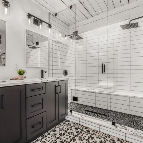 Stylish second bathroom with a double vanity subway tile shower and fun patterned floors.