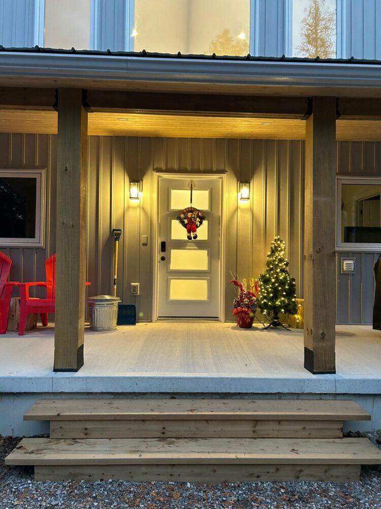 A warm winter welcome—glowing lights, fresh snow, and holiday charm at the cottage door