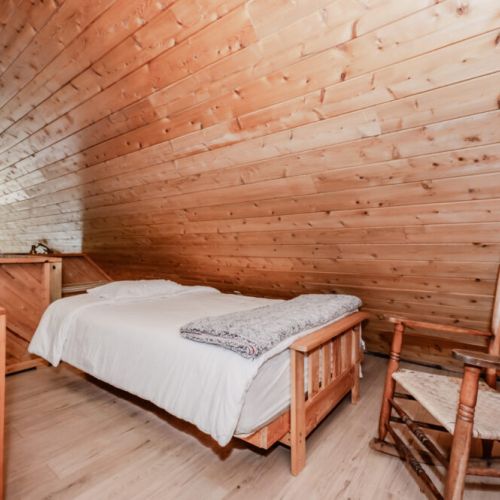 Rustic loft bedroom with cozy wood finishes, perfect for a peaceful lakeside getaway. Enjoy a serene space to relax after a day of adventure.
