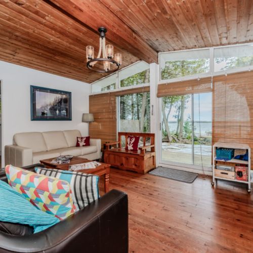 Large windows offer breathtaking lake views from the comfort of the living room—unwind and soak in cottage life.