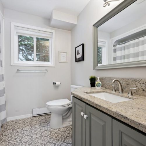 Freshly updated bathroom with granite countertop, modern fixtures, and patterned tile floor