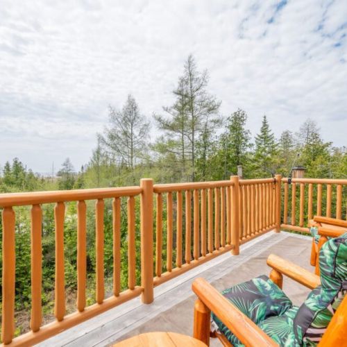 The balcony is furnished with handcrafted log chairs, making it the perfect spot to relax and take in the serene views of the surrounding woodland and waters.