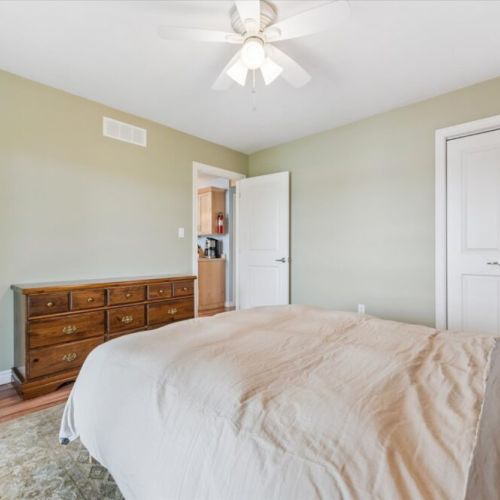 Primary bedroom with warm tones, classic wooden dresser, and convenient access to the main living area.