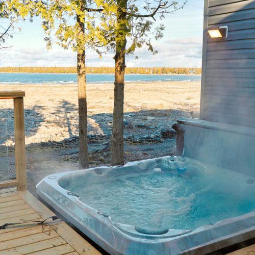 Your lakeside escape: Warm water, fresh air, and steam rising against a beautiful lake backdrop—the perfect invitation to slow down and enjoy cottage life.
