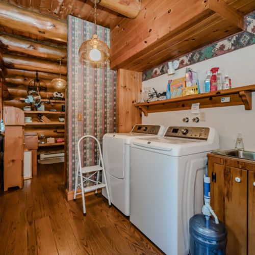 This fully equipped laundry room, complete with rustic log detailing and thoughtful shelving, ensures convenience and functionality during your stay.