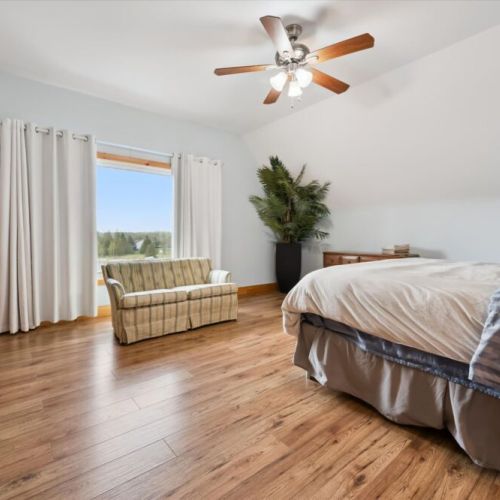 Bedroom 1: Relax in the cozy upstairs loft sitting area, a peaceful spot to read or unwind with views of the trees.
